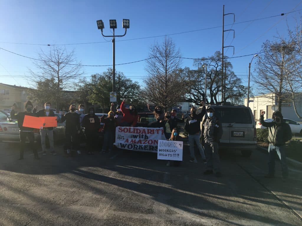 members of a car caravan pose with signs and fists raised